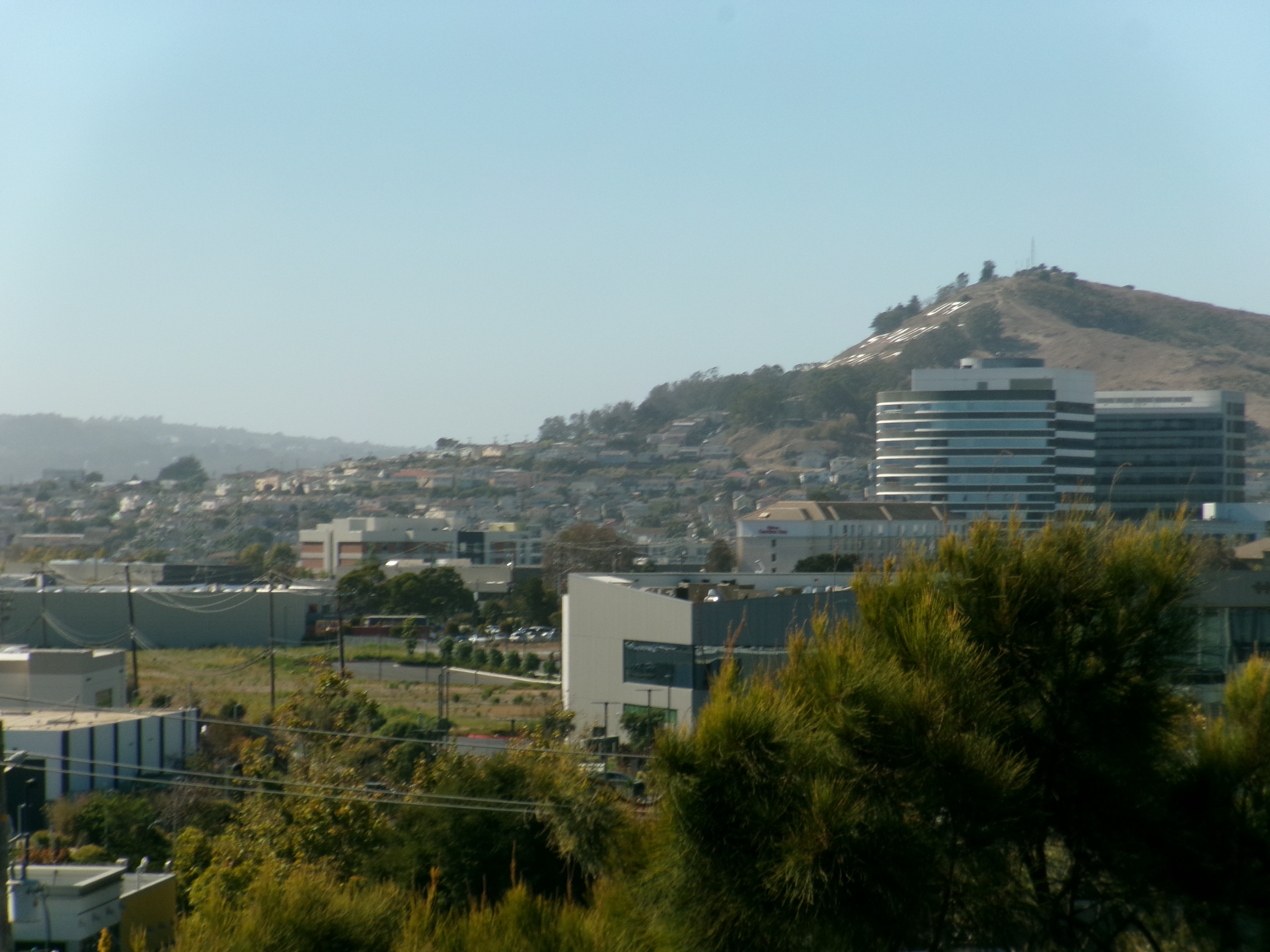 Buildings and hills in South San Francisco beneath a blue sky