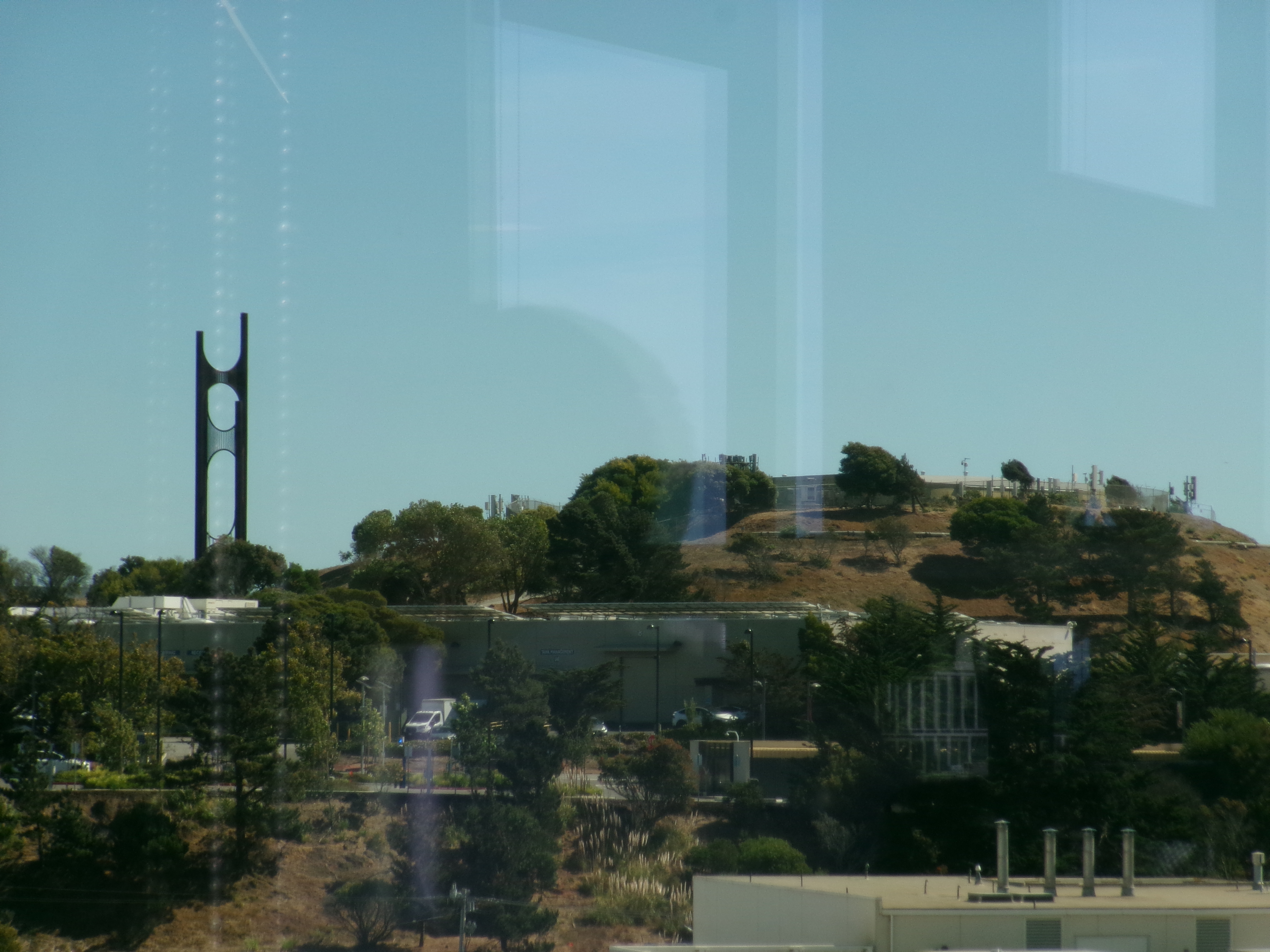 The steel wind harp on a grassy hill above South San Francisco, photographed through a window
