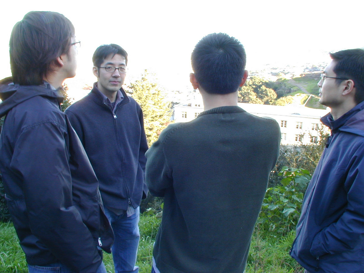 The band ee standing on a grassy hill above San Francisco